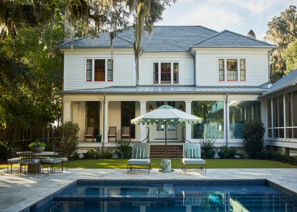 pool with spa blue lounge chairs and cabana umbrella surrounded by low county landscpaing