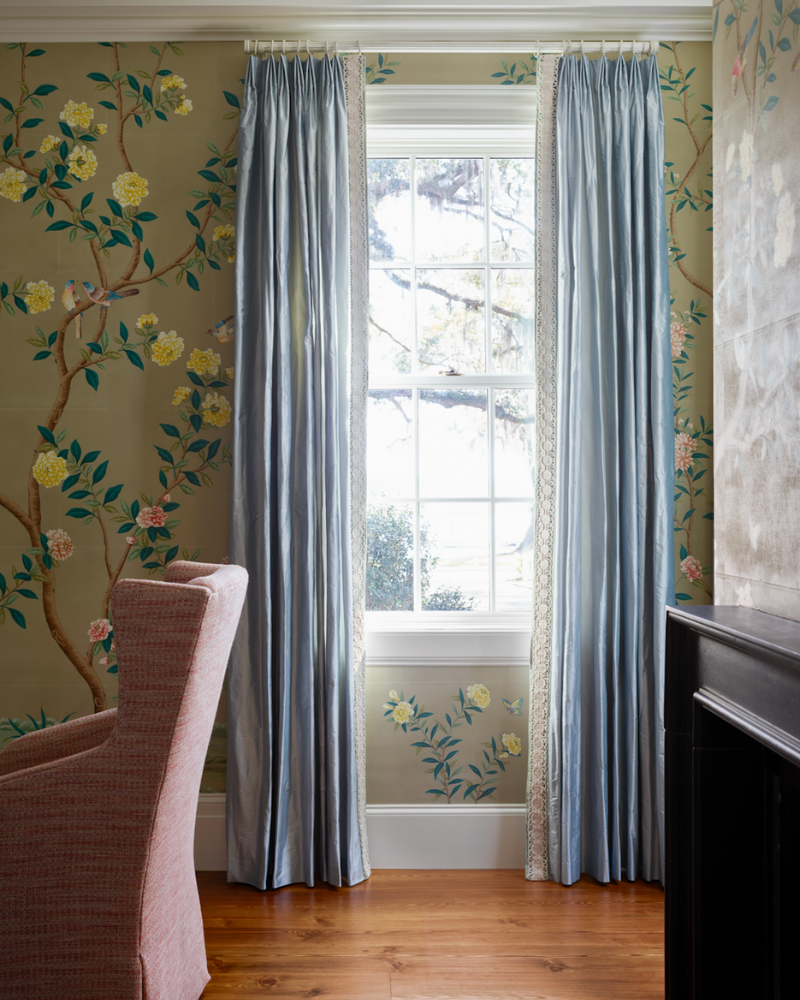 a window surrounded by floral wallpaper and blue curtains in a traditional isle of hope georgia home