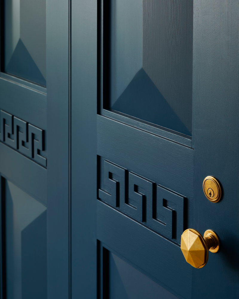 deep blue door with greek key detail and brass knob