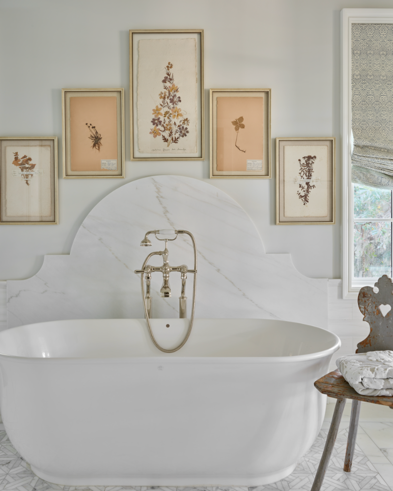 freestanding tub with botanical artwork over it in a traditional isle of hope georgia home