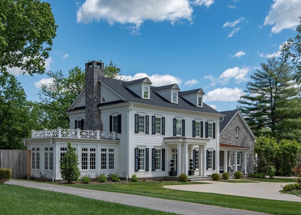 sprawling two story estate with brick and wood siding and chippendale railing
