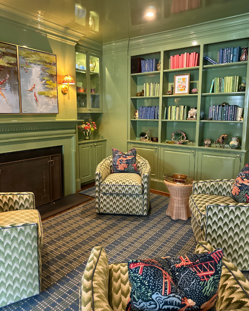 Living room with green lacquered walls and ceiling, four green custom swivel chairs, built-in book shelves and a colorful carpet