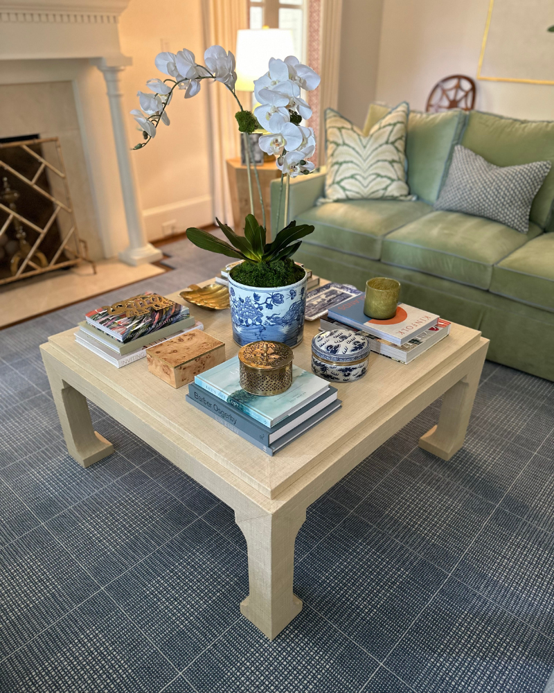 casual elegant living room with grasscloth ming table, green velvet sofa and coffee table books