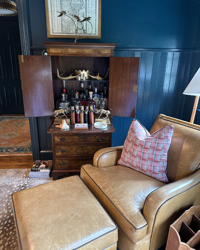 cocktail lounge seating area with leather chair and ottoman and an antique liquor cabinet