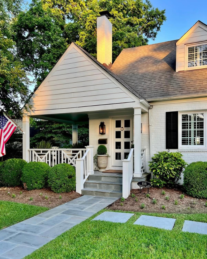 white brick bungalow with chippendale railing and dark shutters in atlanta