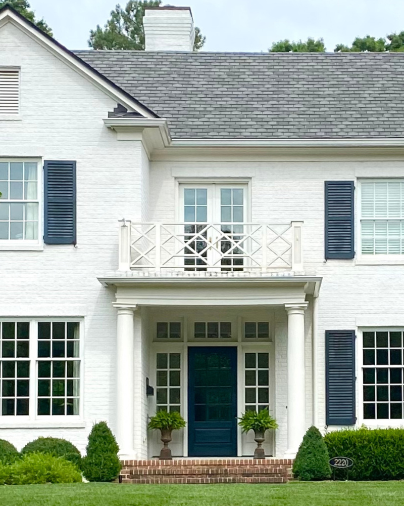 classic white brick, navy shutters, chippendale railing above entrance