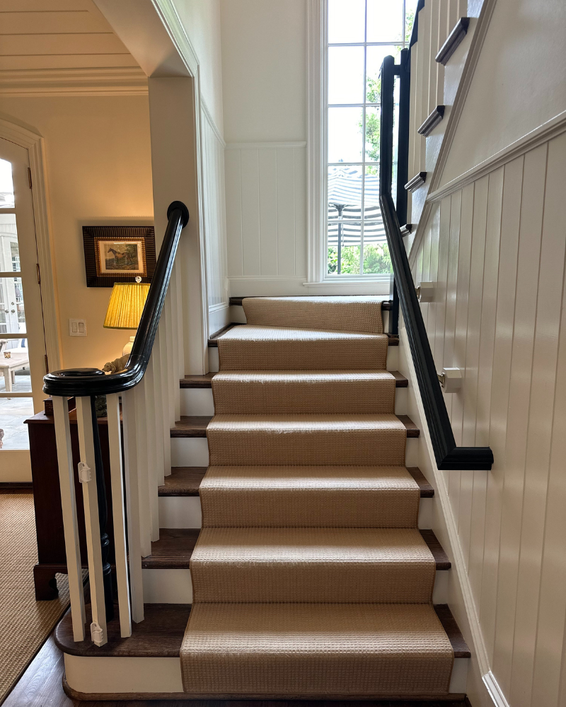 staircase with natural carpet and dark wood rails