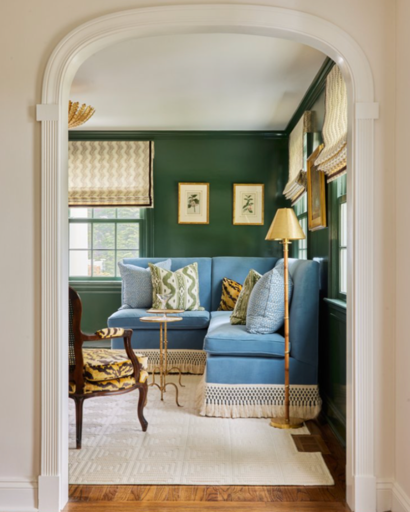 classic arched doorway peeking into sitting room with green walls and light blue velvet corner setee